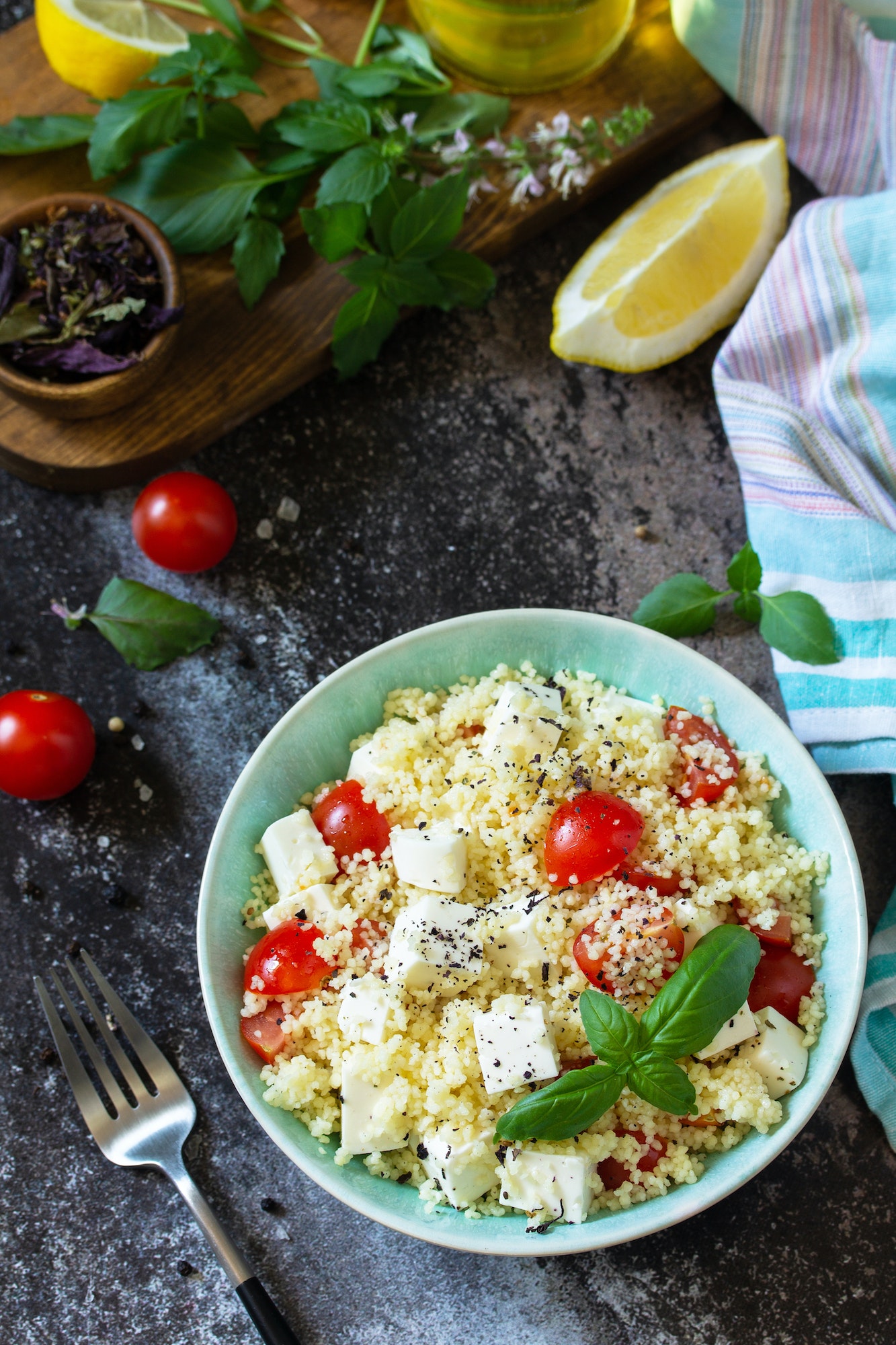 Healthy salad with couscous, tomatoes, feta cheese, basil, chili pepper and olive oil.